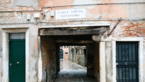 Historic narrow street entrance in Venice, Italy, with aged brick walls and a sign reading CALLE GHETO NOVISSIMO.